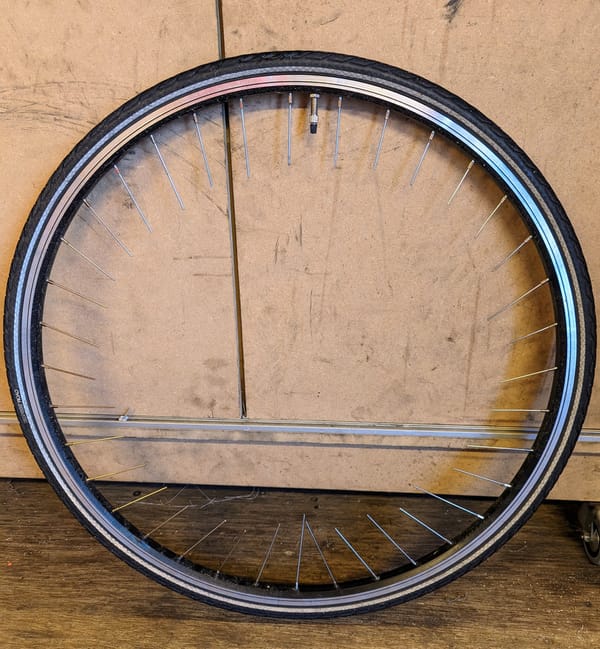 A bicycle wheel, rim and tire, with snipped spokes pointing to the middle